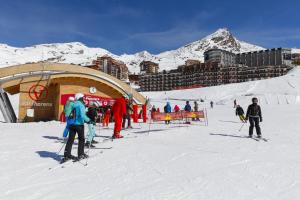 a group of people on skis in the snow near a ski lodge at Résidence Odalys Tourotel in Val Thorens