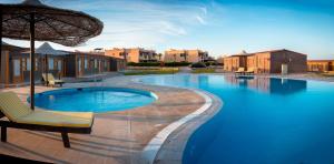 a swimming pool with a chair and an umbrella at Fade Hotel by La Hacienda Ras Sudr in Raʼs Matarma