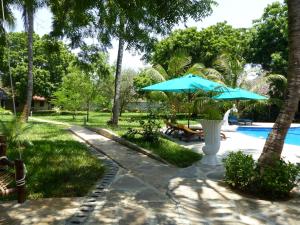 a patio with a blue umbrella next to a pool at Residence Maison Müge in Kilifi
