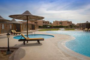 a pool with two lounge chairs and an umbrella next to it at Fade Hotel by La Hacienda Ras Sudr in Ras Matarma +27 photos