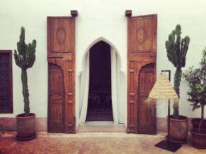 una entrada a un edificio con puertas de madera y cactus en Riad UP, en Marrakech