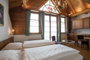 a bedroom with two beds and a table and windows at Meiser Rosenstuben Hotel in Fichtenau