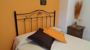 a bed with an orange pillow on top of it at Apartamento Casa Farras in Bonansa