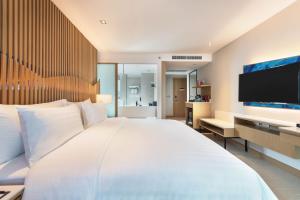 a hotel room with two beds and a television at Mytt Beach Hotel - SHA Extra Plus in Pattaya Central
