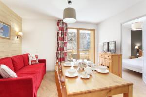 ein Wohnzimmer mit einem Tisch und einem roten Sofa in der Unterkunft Résidence Goélia Le Crystal in Vaujany