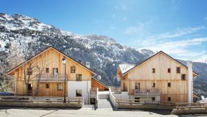 two wooden buildings with mountains in the background at Résidence Goélia Le Crystal in Vaujany