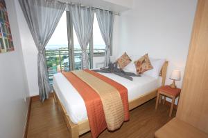 um quarto com uma cama e uma grande janela em Maui Condotel Azure Residence em Manila