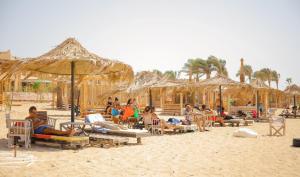 a group of people sitting on the beach under umbrellas at Fade Hotel by La Hacienda Ras Sudr in Ras Matarma