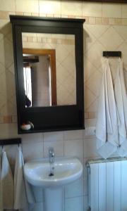 y baño con lavabo, espejo y toallas. en Apartamentos El Sualleiro, en Santa Eulalia de Oscos