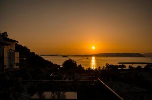 a sunset over a body of water with the sun setting at Hovolo Hotel Apartments in Neo Klima
