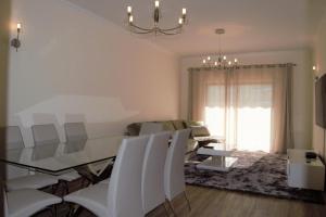 a dining room with a glass table and white chairs at Albufeira Marina Gold in Albufeira +52 photos