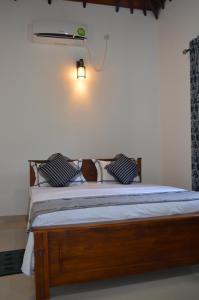 a bed in a bedroom with a light on the wall at Aroma Villa Homestay in Polonnaruwa