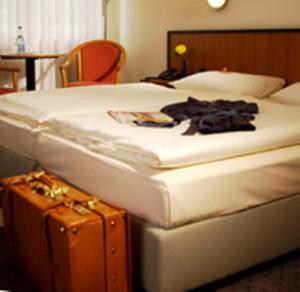 um quarto de hotel com uma cama e uma mala em Andersen Hotel Schwedt em Schwedt