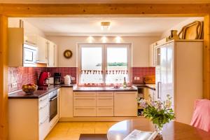 Una cocina con gabinetes blancos y una ventana y una mesa. en Naturidyll auf Rügen, en Putbus