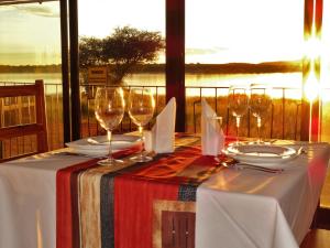 a table with wine glasses and a view of the water at Ovita Wildlife Restcamp in Okazize