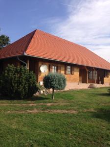 a wooden house with a tree in front of it at Mézesfészer apartman in Cserkút
