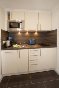 a kitchen with white cabinets and a sink and a microwave at Seewind in Sankt Peter-Ording