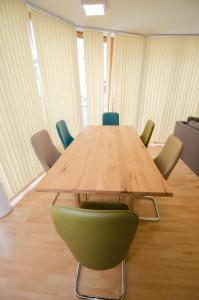 ツェル・アム・ゼーにあるAppartementhaus Zell City by All in One Apartmentsの会議室の木製テーブルと緑の椅子