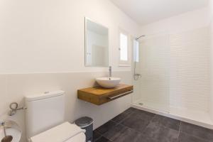 a white bathroom with a sink and a toilet at Apartamentos Gama in Cala Galdana