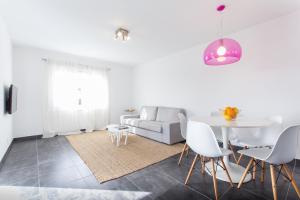 a white living room with a table and a couch at Apartamentos Gama in Cala Galdana