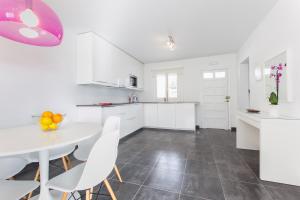 a white kitchen with a white table and chairs at Apartamentos Gama in Cala Galdana