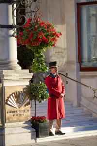 a man in a red coat standing next to a plant at Mandarin Oriental Hyde Park, London in London