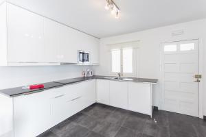a white kitchen with white cabinets and a sink at Apartamentos Gama in Cala Galdana