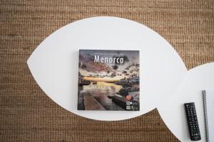 a magazine on a table with a remote control at Apartamentos Gama in Cala Galdana