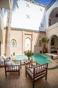 a courtyard with a swimming pool with two benches at Riad Amira in Marrakesh