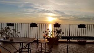 a balcony with a table and a bench and the sunset at Residenza d'Epoca Borgodifiume in Fiumefreddo Bruzio