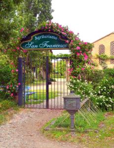un portail avec un panneau en face d'un jardin dans l'établissement Agriturismo Borgo San Francesco, à Basiglio