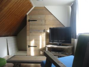 a living room with a tv and a wooden cabinet at Holiday Home Emmastraat in Katwijk