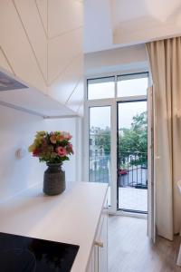 a white kitchen with a vase of flowers on a counter at 9010 Apartments in Vilnius
