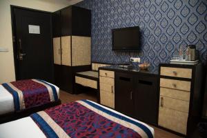 ein Hotelzimmer mit 2 Betten und einem TV in der Unterkunft The Oakland Plaza by Orion Hotels in Neu-Delhi