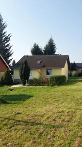 una casa con un campo de hierba delante de ella en Ferienhaus Feldmann en Schmiedefeld am Rennsteig