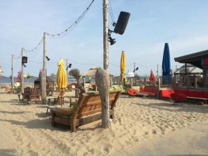 a beach with benches and umbrellas on the sand at Holiday Home Emmastraat in Katwijk