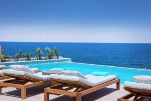 パノルモス・レティムノにあるThalassa Residence, a luxury coastal escape, By ThinkVillaのラウンジチェア付きのスイミングプールと海