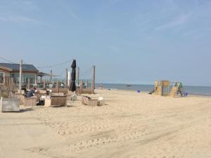 a beach with chairs and an umbrella and the ocean at Holiday Home Emmastraat in Katwijk +9 photos