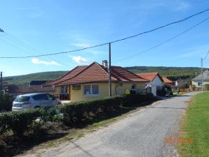 a house with a car parked on the side of a road at Tündér Szálló in Eplény