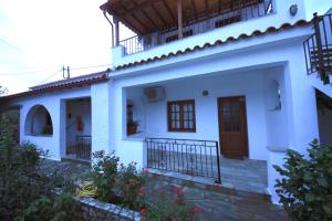 a white house with a door and a balcony at Amalia Studios in Skiathos