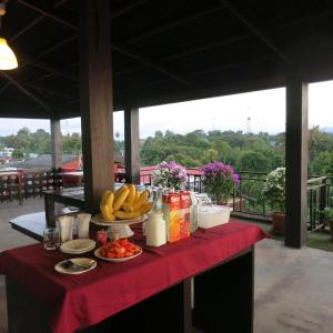 Yoont Hotel في Ban Khun Yuam: طاولة مع الفاكهة والمشروبات على قطعة قماش الطاولة الحمراء