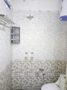 a bathroom with a toilet and a tiled wall at Hotel Golden Crown Laxman Jhula in Rishīkesh
