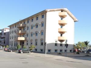 um grande edifício branco com carros estacionados em frente em Guest House Dabi em Kruševac