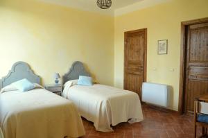 バジーリオにあるAgriturismo Borgo San Francescoの黄色い壁の客室内のベッド2台