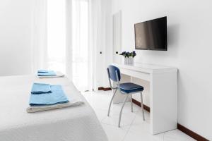 a white bedroom with a desk and a tv on a wall at B&B Cozy Cove in Torre del Greco