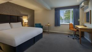 Sketchley Grange Hotel في هينكلي: غرفه فندقيه بسرير ومكتب ونافذه