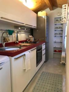 una cucina con armadi bianchi e piano di lavoro rosso di Appartamento Porta Saragozza a Bologna