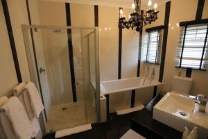 a bathroom with a glass shower and a sink at Villa Moringa Guesthouse in Windhoek
