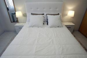 1 cama blanca grande con 2 lámparas en 2 mesas en Apartamento junto al Duero en la Sierra de Urbión, en Molinos de Duero