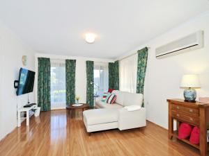 a living room with a white couch and a tv at Moana Magic - C21 SouthCoast Holidays in Moana